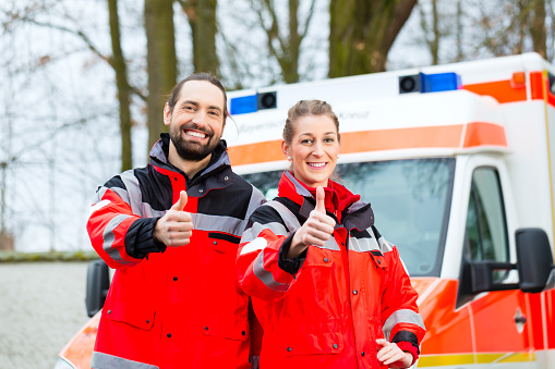 Emergency doctor and nurse standing in front of ambulance