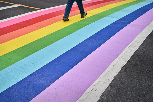 Crossing the street on a multi colored crosswalk painted with the colors of the pride flag.