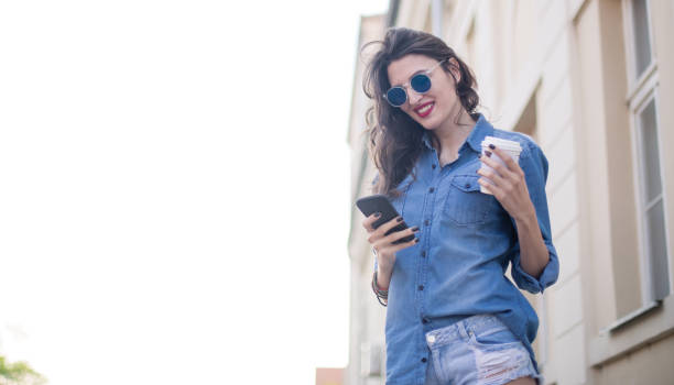 istock Woman using smart phone and holding coffee 820132050