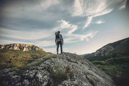 Rear view of a young handsome man hiking on the mountain