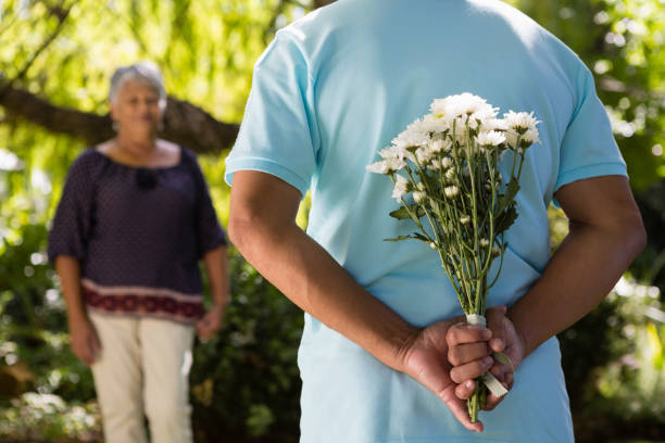 istock Mid-section of senior man hiding flowers behind back 820171036