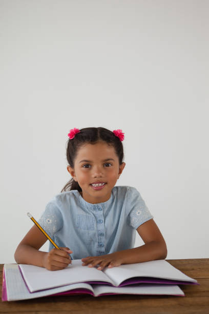 istock Young girl writing in her book against white background 820171306