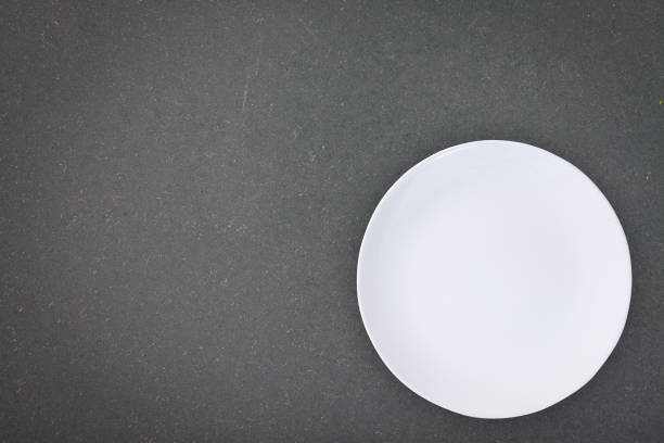 istock Top view of an empty white plate placed on a blackboard with copy space. 820179006