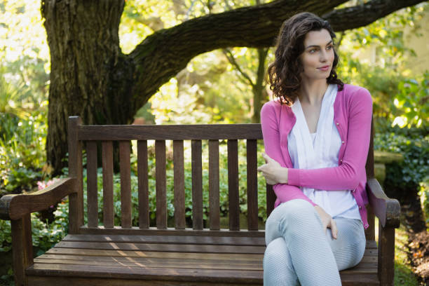 istock Smiling beautiful woman sitting on bench in park 820209494