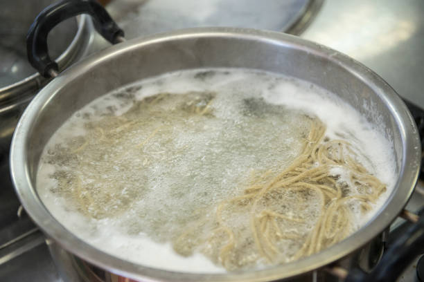 Soba noodles boiled in water on top of a stove stock photo