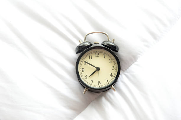 istock Alarm clock on bed in morning with sun light, soft and select focus 820213290