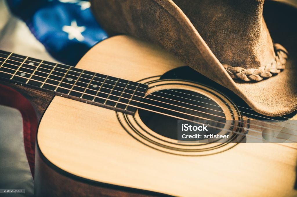 Country and western music. Acoustic Guitar and Cowboy Hat with American Flag on Background Country and Western Music Stock Photo