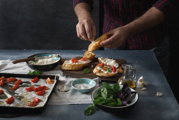 istock Man preparing an Italian bruschetta with baked tomatoes, basil and cheese 820261232