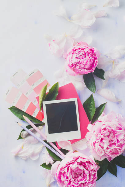istock Minimal styled flat lay with peony flowers, blank photo frame and pink notebook. 820261544