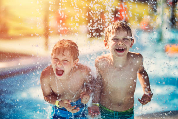 Little boys having fun in waterpark Little boys having fun in splash pool in a waterpark. Laughing and screaming boys are being splashed by water.
 children only stock pictures, royalty-free photos & images