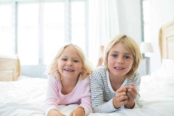 istock Happy siblings relaxing on bed in bedroom 820305230