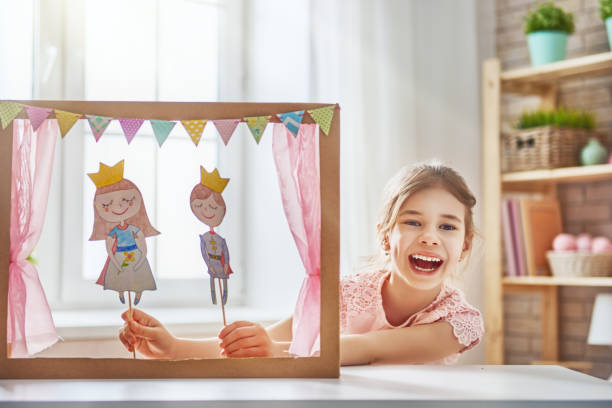 performance in the puppet theater Happy girl plays with performance in the puppet theater with prince and princess at home. Funny lovely child is having fun in kids room. puppet stock pictures, royalty-free photos & images