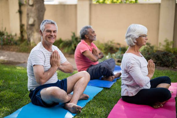istock Smiling senior man meditating in prayer position with friends 820325002
