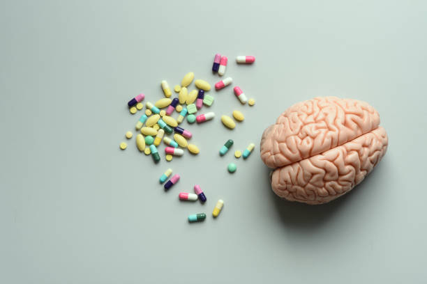 Colorful medicine in tablets and capsules with brain model on table stock photo