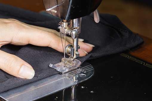 close-up hand working with old sewing machine