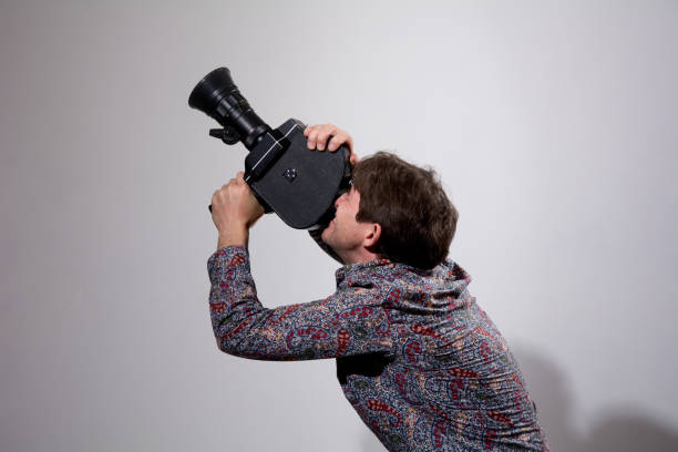istock A man with an old movie camera on a gray background. 820347196