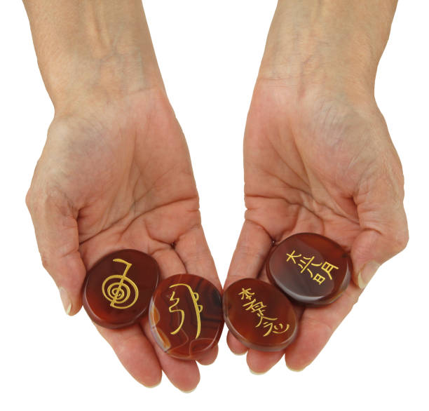 Reiki Symbols etched onto polished Carnelian stones Female hand with palms open showing four Reiki symbols isolated on white background Carved Carnelian stock pictures, royalty-free photos & images