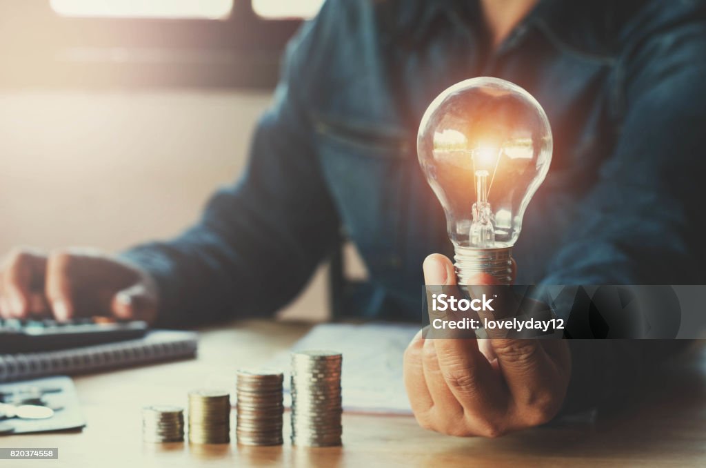 business accountin with saving money with hand holding lightbulb concept financial background Savings Stock Photo