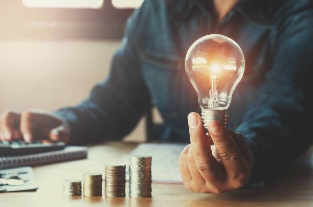 business accountin with saving money with hand holding lightbulb concept financial background - bank currency stack coin imagens e fotografias de stock