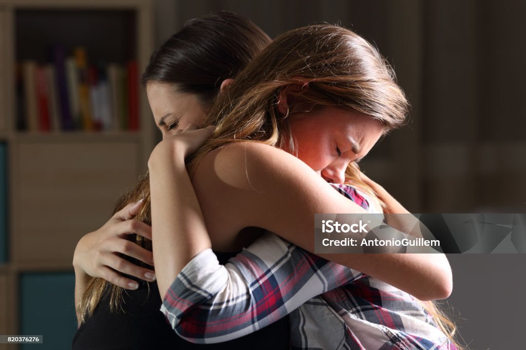 Due adolescenti tristi che si abbracciano in camera da letto - Foto stock royalty-free di Abbracciare una persona