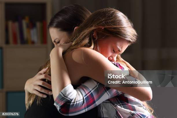 Due Adolescenti Tristi Che Si Abbracciano In Camera Da Letto - Fotografie stock e altre immagini di Abbracciare una persona