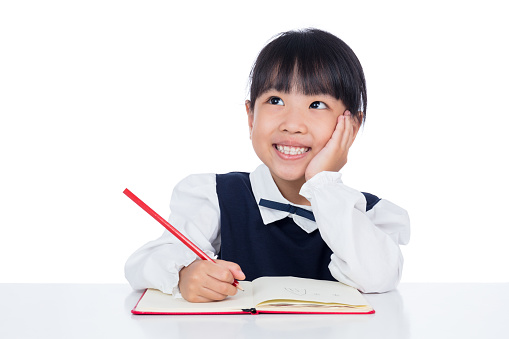 Asian Little Chinese girl writing homework in isolated white background