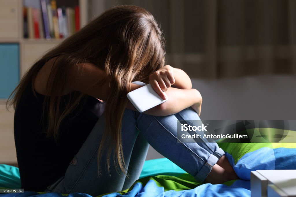 Triste teen com um telefone no quarto dela - Foto de stock de Adolescente royalty-free