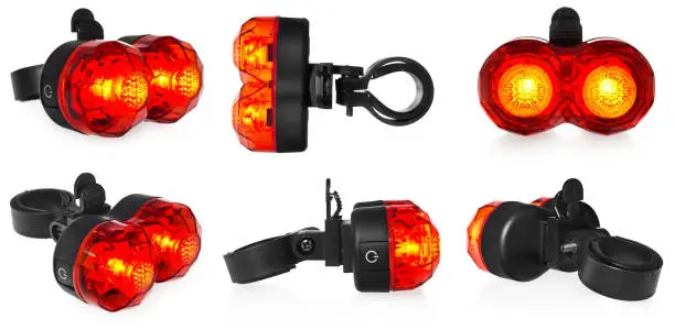 Illuminated rear bike lamp. Lighting in red color. Bicycle mounting black plastic. Equipment on a white background with a slight reflection.