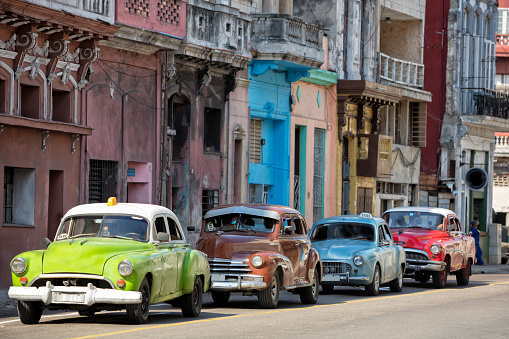 Vintage American cars speeding in front of dilapidated buildings in traditional colonial style, Havana, Cuba, 50 megapixel image