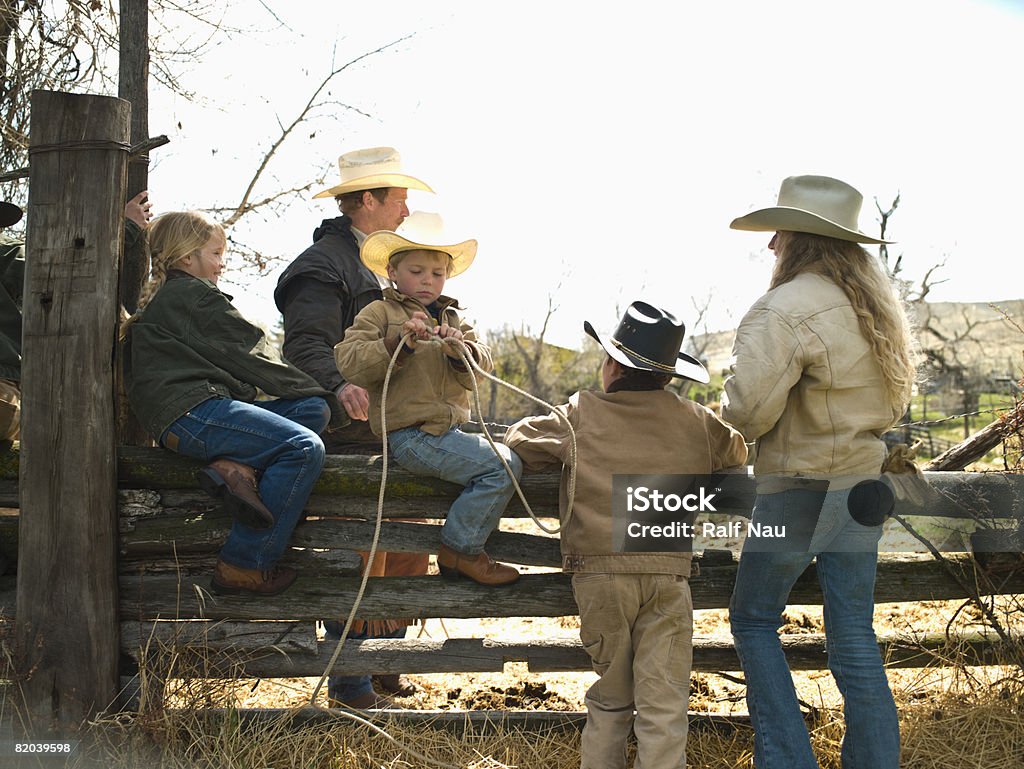 Kids sitting on fence Siblings and father sitting on fence of corral in Big Timber, Montana American Culture Stock Photo