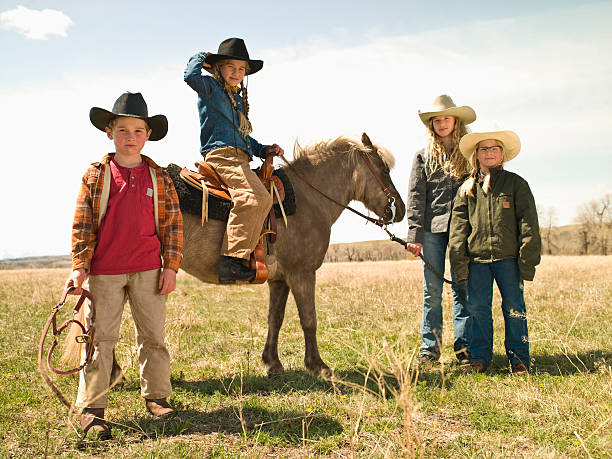 Brother and sisters with Shetland pony Sibling riding Shetland pony on family ranch in Big Timber, Montana pony boy pictures stock pictures, royalty-free photos & images