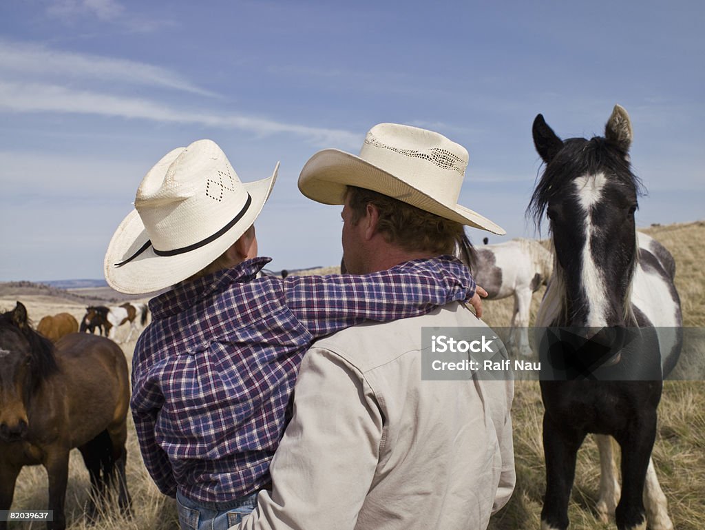 Père portant son fils sur le ranch de chevaux - Photo de Montana - Ouest Américain libre de droits