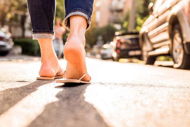 woman wearing flipflops walking down the street on a sunny summer day- closeup of the feet - sensuality walking women beautiful imagens e fotografias de stock