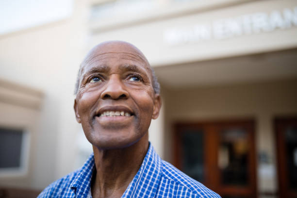 istock Thoughtful senior man smiling while looking up at nursing home 820398886