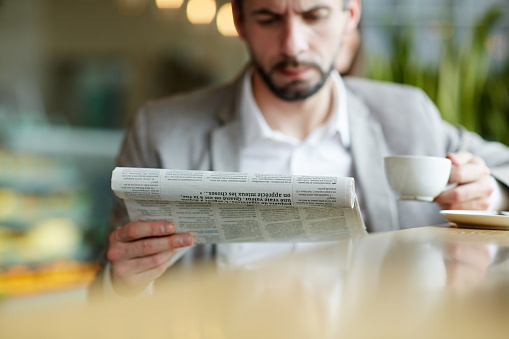 Business leader with cup of tea reading fresh news in paper