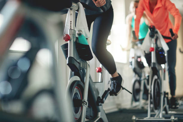 Embrace the power of a bike Cropped shot of women working out with exercise bikes in a exercising class at the gym exercise bike stock pictures, royalty-free photos & images