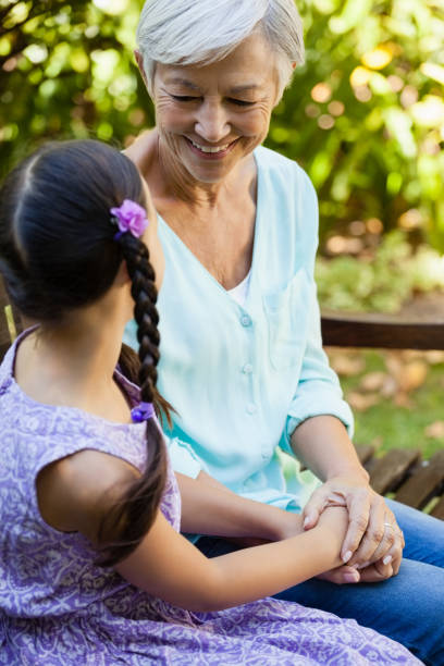 avó da neta, as mãos enquanto está sentado no banco a sorrir - generation gap multi generation family vertical holding hands - fotografias e filmes do acervo