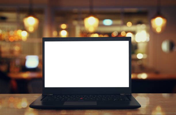 istock open laptop with white screen on wooden table in front of abstract blurred restaurant lights background. 820425624