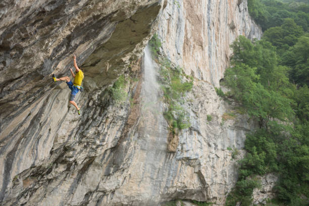istock Man hanging on sfatey rope while climbing on  rock face 820448526