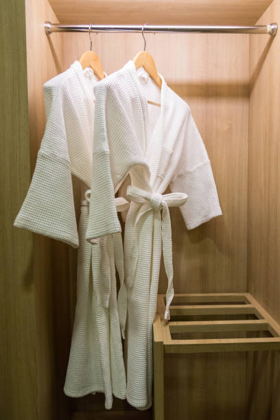 istock two off white color bathrobes hanging in warmly design closet, room for copy space 820449256