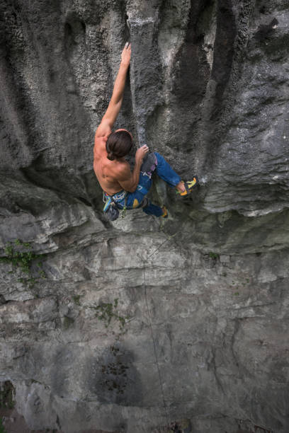 istock Male climber hanging in one hand on rock wall cavity 820454158
