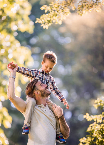istock Happy father communicating with his son while carrying him on shoulders in nature. 820455476