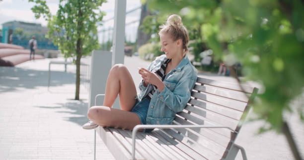 Young caucasian woman using phone in a city park. stock photo