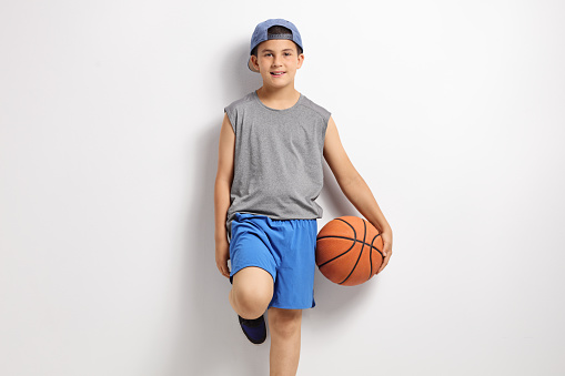 Boy with a basketball leaning against a wall