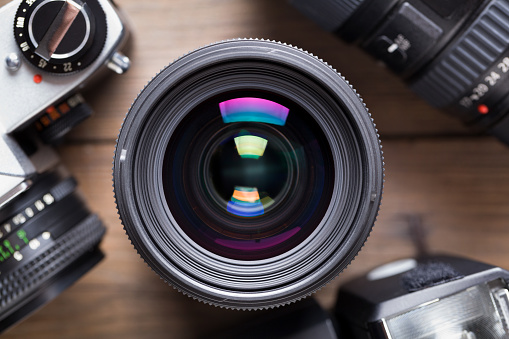 Camera lens on wooden table. This file is cleaned and retouched.