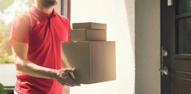 home delivery service - deliveryman with boxes standing by the house doors