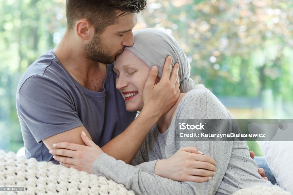 Sick woman being kissed Young sick woman being kissed on the head Patient Stock Photo