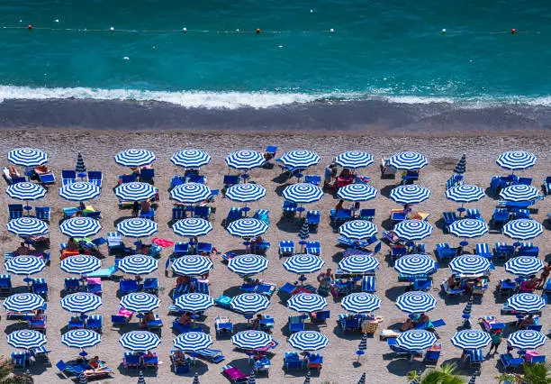 Aerial view of the amazing beach with colorful umbrellas and people who sunbathe