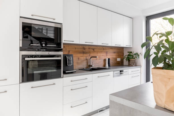 Balanced kitchen with natural accents Balanced kitchen with white cabinets grey worktop and natural accents symmetry stock pictures, royalty-free photos & images