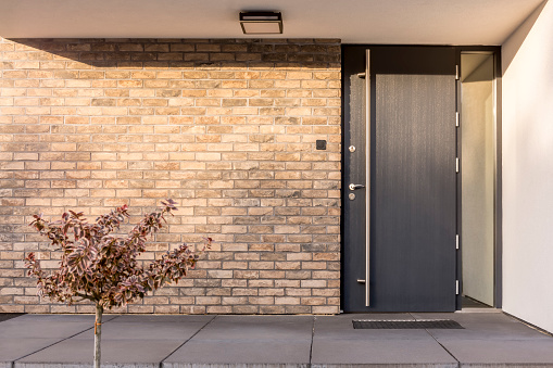 Calgary, Alberta, Canada- July 16,2022:  Large gate across driveway that leads up to home. Stone pillars on either side. Xeriscaped landscaping at side of gate and driveway.